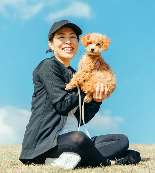 芝生の上で犬を抱く女性の写真